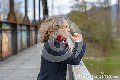 Thoughtful woman gazing out from a bridge Stock Photo