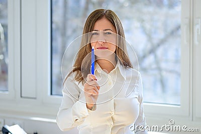 Thoughtful woman gesturing with her pen as she frowns at the camera Stock Photo