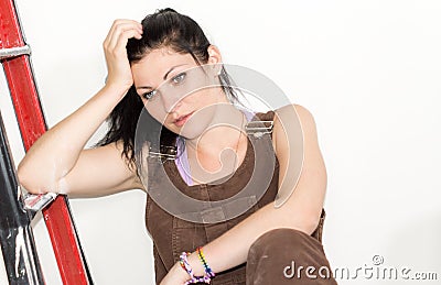 Thoughtful woman leaning on a stepladder Stock Photo