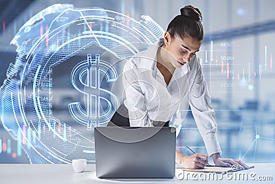 Thoughtful young european businesswoman leaning and writing on desktop with laptop and glowing dollar hologram on bright blurry Stock Photo