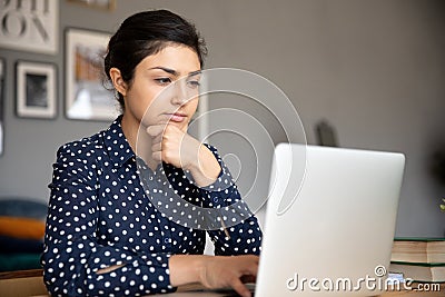 Thoughtful young indian woman looking at computer screen. Stock Photo