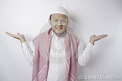 A thoughtful young Muslim man shrugging his shoulders, gesturing confusion isolated by white background Stock Photo