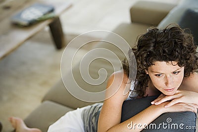 Thoughtful Young Woman Sitting On Couch Stock Photo