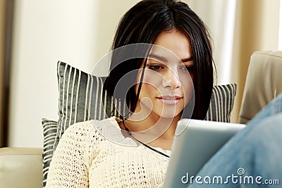 Thoughtful young woman using tablet computer at home Stock Photo