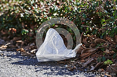 Thoughtlessly thrown away protective mask against SARS-Covid-19, which is lying on the ground as garbage by the roadside Stock Photo