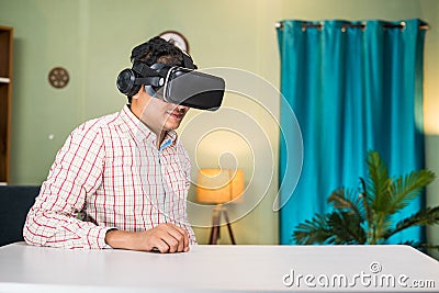 thougtful Young man with virtual reality headset looking empty table at home - concept of modern technology, cyberspace Stock Photo