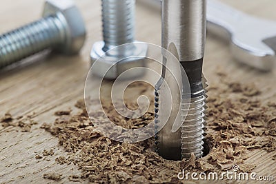 Thread tap drill cutting hole in wooden plate. Working cutter Stock Photo