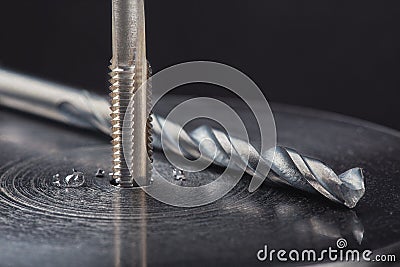 Thread tap drill steel billet with drill bit on background. Working cutter Stock Photo