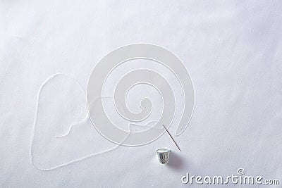 Threading needle thread forming a heart background top view Stock Photo