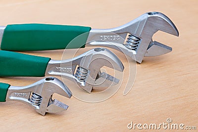 Three adjustable wrenches in row on wood Stock Photo