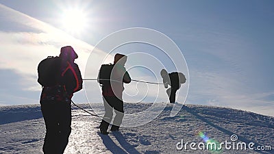 Three Alpenists climb rope on snowy mountain. Tourists work together as team shaking heights overcoming difficulties Stock Photo