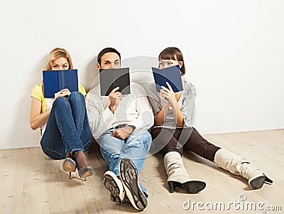 Three amused friends with books Stock Photo