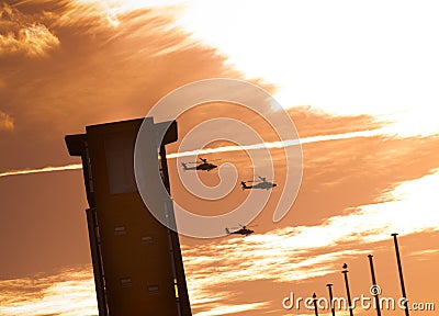 Three apache helicopters flying past a tower with clouds Stock Photo