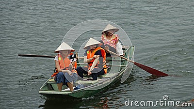 Three Asian women paddling a wooden boat along the scenic river in Vietnam. Editorial Stock Photo