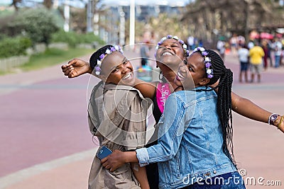 Three beautiful black young women laughing and celebrating a birthday outdoors in Durban, South Africa Editorial Stock Photo