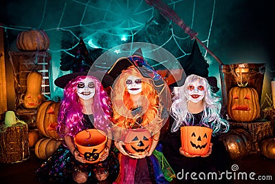 Three cute funny sisters celebrate the holiday. Jolly children in carnival costumes ready for Halloween. Stock Photo