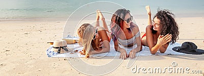 Three beautiful happy young women girlfriends on the seashore in bikini standing lying on a tropical beach enjoying vacation Stock Photo