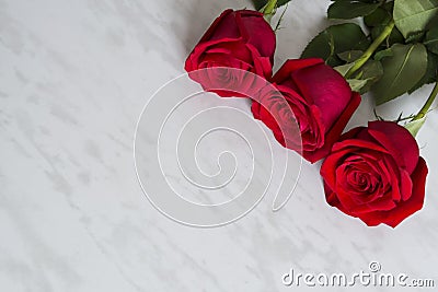 Three beautiful red roses on a marble table. Copy space Stock Photo