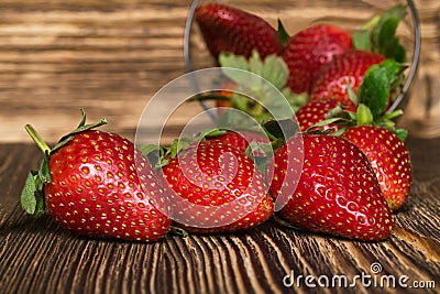 Three beautiful strawberries lying on dark board, amid bowls Stock Photo