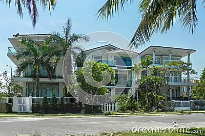 Three beautiful three-story houses with palm trees, trees, in the summer Stock Photo