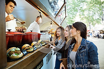 Three beautiful young women buying meatballs on a food truck. Stock Photo