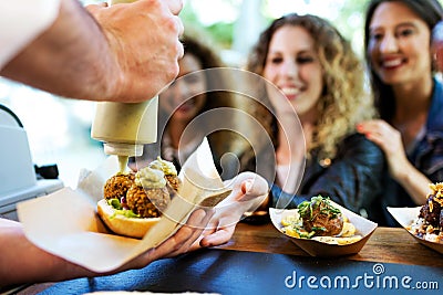 Three beautiful young women buying meatballs on a food truck. Stock Photo