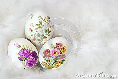 Three beautifully decorated Easter eggs in white feather background, with copy space; decoupage technique Stock Photo