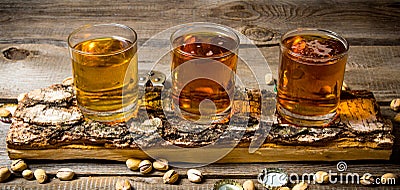 Three beers on birch stand with pistachios around. Stock Photo