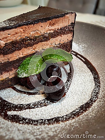 Three berries with green leaf in front of a piece of cake Stock Photo