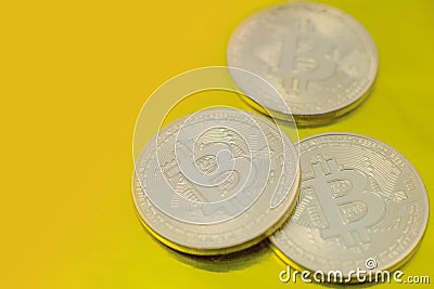 Three bitcoins placed on a yellow background Stock Photo