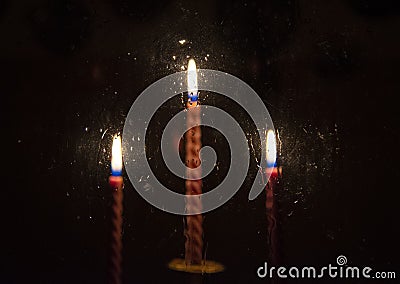 Three blurred red candles burning in the darkness outside the window Stock Photo