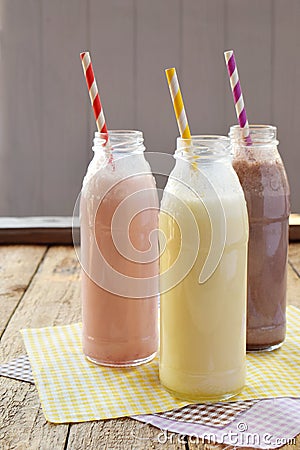 Three bottle of various milkshakes chocolate, strawberry and vanilla . Healthy smoothie with straw. Tasty milk shake cocktails. Stock Photo