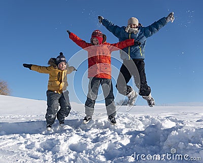 Three boy family friends joyfully jump into the sky over snow drifts in the winter, children play Stock Photo