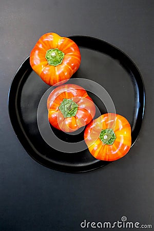 Three red photographed from top peppers in a round black dish Stock Photo
