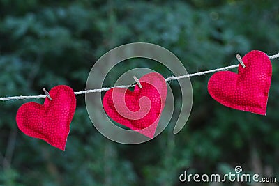 Three bright red hearts hanging on clothesline outdoors Stock Photo