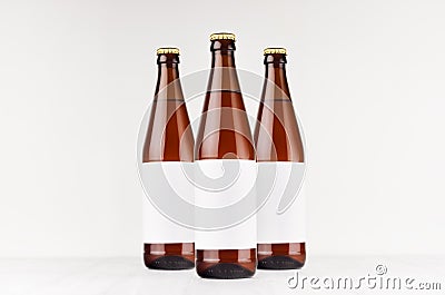 Three brown NRW beer bottles 500ml with blank white label on white wooden board, mock up. Stock Photo