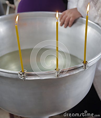 Three burning candles on the edge of the silver font before the Orthodox rite of baptism of a child Stock Photo