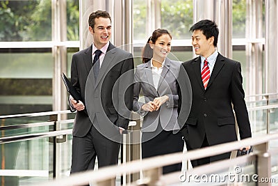 Three Business Colleagues Chatting Walking Stock Photo