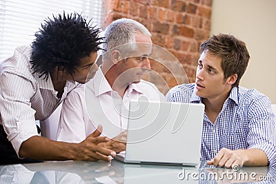 Three businessmen in office with laptop Stock Photo