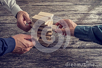 Three Businessmen Playing Wooden Tower Game Stock Photo