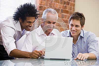 Three businessmen sitting in office with laptop Stock Photo