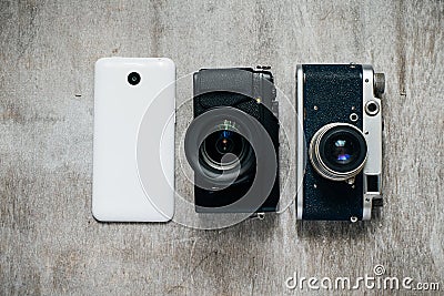 Three camera retro and modern mobile phone on a light gray background Stock Photo