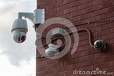 Three Security Cameras Mounted on a Red Brick Wall Stock Photo