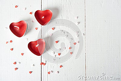 Three candles in the form of red heartbeats on a white background and scattered confetti Stock Photo