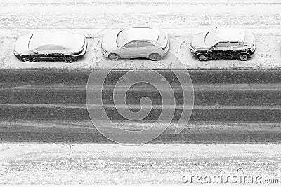 Three cars under snowfall are parked on the road Stock Photo