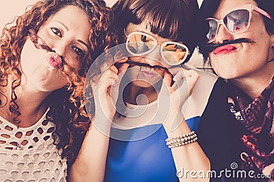 Three caucasian females friends stay together in friendship and craziness using hair like moustache and happiness relationship Stock Photo