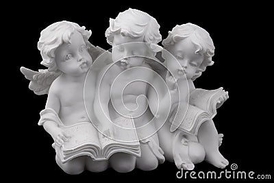 Three ceramic white angels read the book, dreaming and thinking. Stock Photo