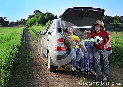 Three cheerful child sitting in the trunk of a car Stock Photo