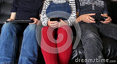 Three children playing with electronic devices - tablet, smartphone and games controller Stock Photo