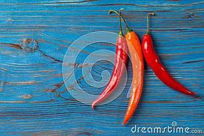 Three chilli peppers on blue wooden background Stock Photo